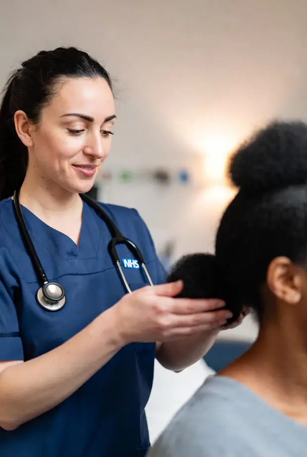 A nurse gently caring for a patient's Black heritage hair on a hospital ward